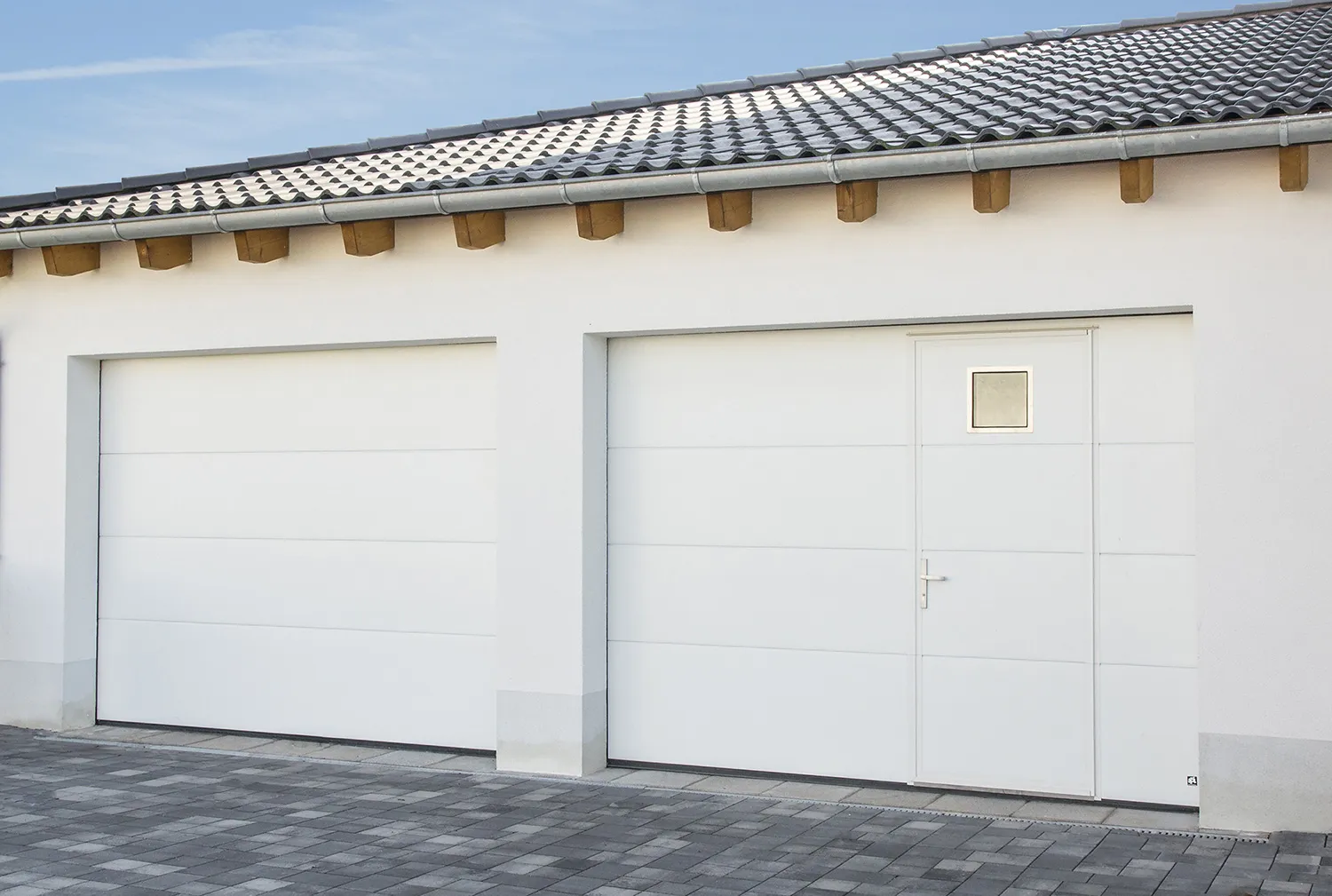 Zwei weiße Garagentore, eines mit integrierter Schlupftür
