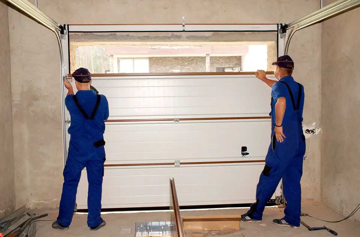 Zwei Monteure bauen ein Garagentor ein